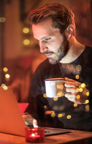 Man Holding Mug in Front of Laptop